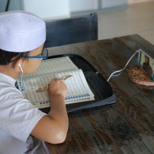 Asian kid reading Al-Quran through video call during education